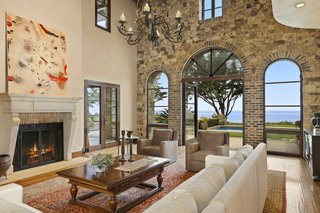 The soaring great room features a large fireplace and elegant arched windows opening to the pool and ocean beyond.