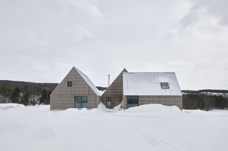 Sitting on a plateau over the rolling landscape of rural Quebec, the residence comprises three joined, gable roof structures, each oriented differently. It takes inspiration from the local farmhouses and barns of the area, whose steep rooflines help shed snow in the winter, and whose wood-clad facades traditionally used lumber from local trees.