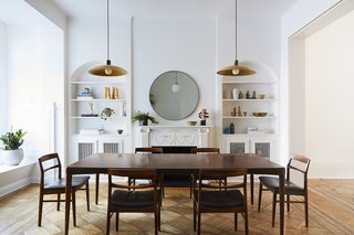 "The dining room is a transitional space between the old and new—in this space
we simplified the material palate, painting all decorative woodwork matte white to emphasize its geometry over its materiality," say the architects. The room holds a midcentury dining set and pendent lights from Raco.