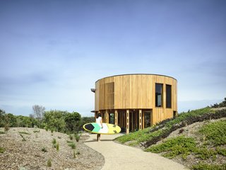 Wild bush, sand dunes, and scrub surround the circular home on Victoria’s Mornington Peninsula. The Austin Maynard Architects team was careful to minimize the building’s impact on the fragile landscape.