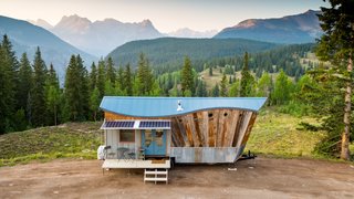 High in the Colorado mountains, this completely off-grid home cleverly fuses art and functionality. Home to a young couple and their two dogs, the eye-catching dwelling showcases the impeccable craftsmanship and creative flair of its occupants. Greg and Stephanie Parham built San Juan Tiny House to include a wavy roof, an angled front prowl, barn wood siding arranged like the rays of the sun, blue ombré shakes on the rear wall, reclaimed materials throughout, and a collapsible front porch, which features a fold-up deck and fold-down awning. On the inside, clever solutions maximize square feet and storage.