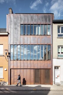Copper cladding will patina over time. Horizontally articulated windows and standing seams give the facade a sleek, streamlined presence.