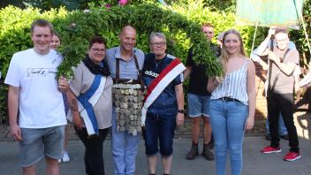 Das neue Königsgespann ließ sich feiern: Unter einer großen Krone, flankiert von der Gildefahne, schritten (v.l.) Nicole Göser, Jörg Kolz und Gaby Borchert durchs Dorf.