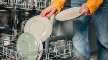 Woman unloading washed plates from dishwasher at home model released, Symbolfoto property released, VSNF01773