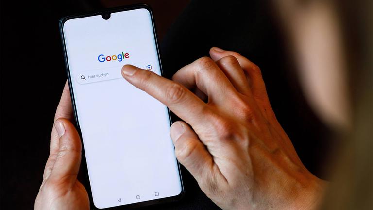 Ein Finger tippt auf das Feld der Google-Suche auf einem Smartphone.
