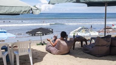 Ein ausländischer Tourist sitzt am Strand Kuta Beach in Bali.