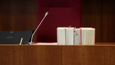 Auf einem Tisch in einem Bonner Gerichtssaal stehen Gesetzestexte.