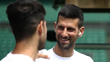 Serbia's Novak Djokovic smiles at Spain's Carlos Alcaraz during a warm up session on centre court at the All England Lawn Tennis Club, in west London on June 27, 2024, the week before the Wimbledon Championships tennis tournament is due to start on July 1. (Photo by HENRY NICHOLLS / AFP) / RESTRICTED TO EDITORIAL USE