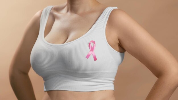 Młoda dama w białym topie ze wstążką na piersi, aby wspierać różowy Październik i kobiety walczące z rakiem piersi Anonimowe zdjęcie studyjne na beżowym tle