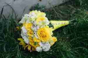 Bezpłatne zdjęcie bukiet ślubny z żółtymi różami leżącymi na trawie