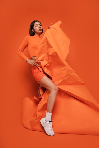 Bezpłatne zdjęcie cała kobieta pozująca w pomarańczowym stroju