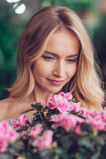 Bezpłatne zdjęcie close-up kobiety twarz patrzeje różowych kwiaty