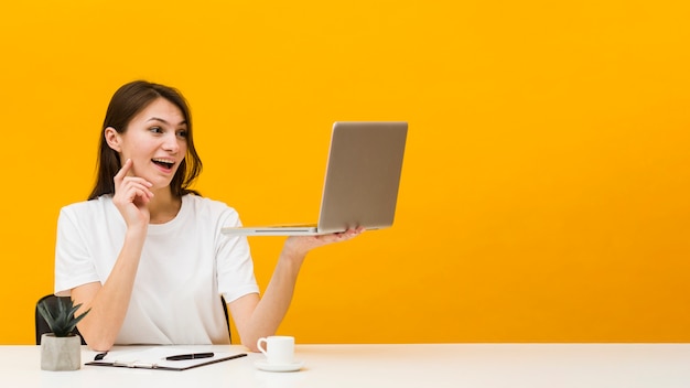 Bezpłatne zdjęcie frontowy widok kobieta cieszy się przy biurkiem z kopii przestrzenią kobieta przy biurkiem
