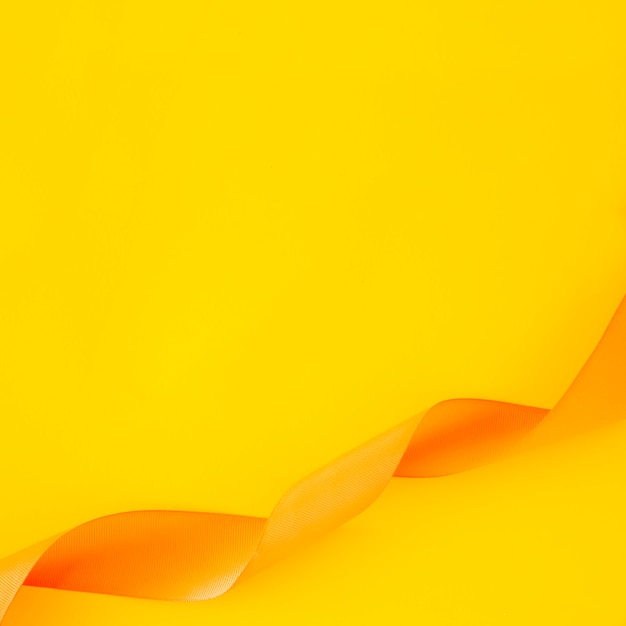 Bezpłatne zdjęcie fryzujący atłasowy faborek na żółtym tle