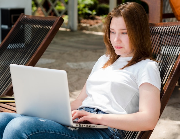 Bezpłatne zdjęcie kobieta relaksująca w krześle pracuje na laptopie