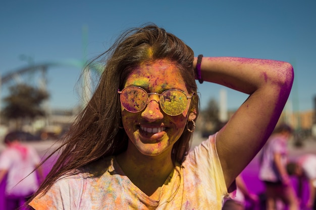Bezpłatne zdjęcie portret jest ubranym okulary przeciwsłonecznych zakrywających z holi kolorem uśmiechnięta młoda kobieta
