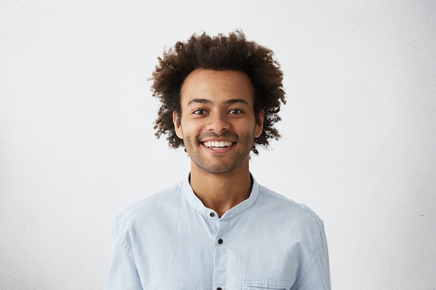 Bezpłatne zdjęcie pozytywny facet z afrykańską fryzurą i ciemną skórą w eleganckiej białej koszuli