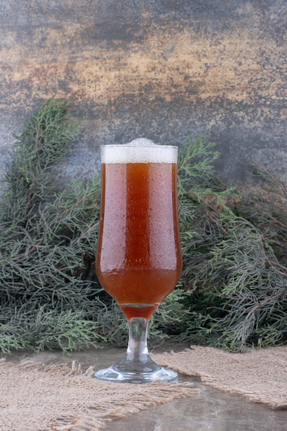 Bezpłatne zdjęcie szklanka ciemnego piwa na płótnie z gałązką sosny