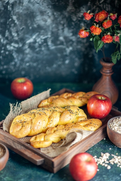 Bezpłatne zdjęcie widok z przodu paluszki chlebowe z dzianiny na prostokątnej desce drewnianej jabłka kwiaty w wazonie na stole