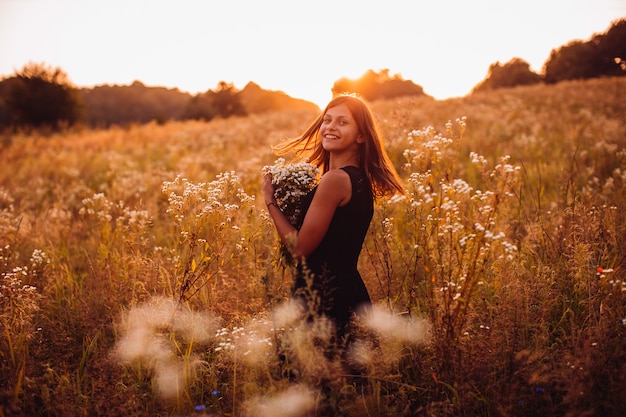 Foto grátis mulher feliz com flores fica no campo da noite