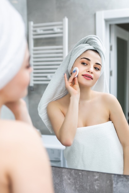 Foto grátis mulher feliz removendo esponjas de limpeza de maquiagem, loção, espelho de banheiro no banheiro
