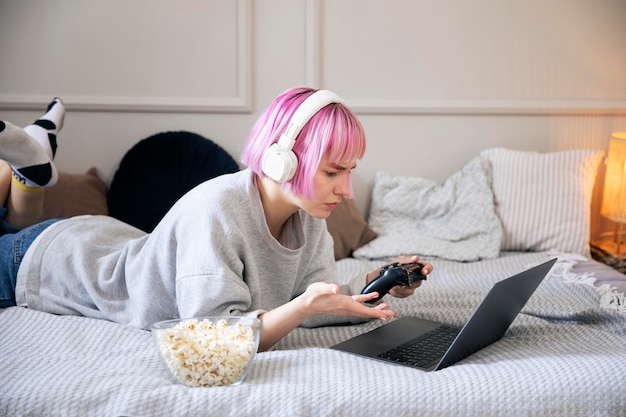 Foto grátis mulher jovem com cabelo rosa brincando com um joystick no laptop