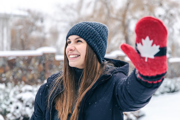 Foto grátis mulher jovem feliz com luvas vermelhas com a bandeira do canadá em clima de neve