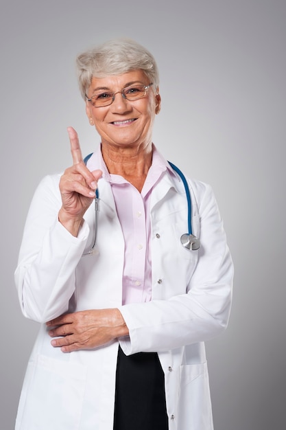 Foto grátis médico sênior sorridente apontando com o dedo
