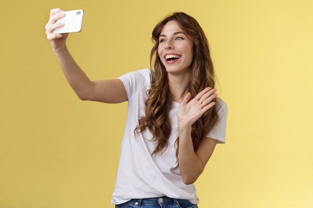 Foto grátis amigável animada de boa aparência alegre menina feminina estender o braço segurar smartphone gravar vídeo blog wavi ...