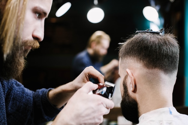 Foto grátis barbeiro remove o cabelo do homem com um clipper
