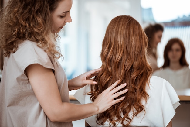 Cabeleireiro feminino fazendo penteado para mulher ruiva no salão de beleza
