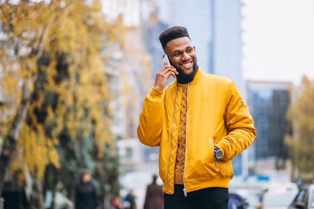 Estudante americano africano andando na rua e falar ao telefone