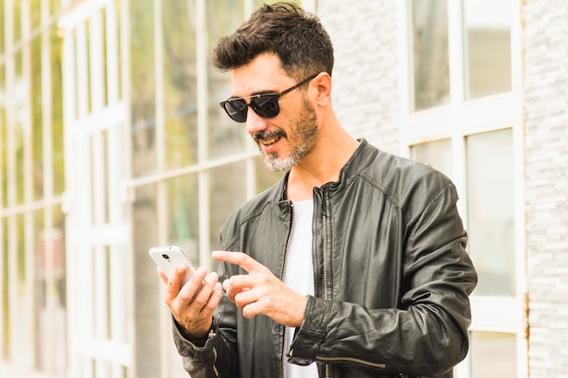 Foto grátis homem, em, casaco preto, desgastar, óculos de sol, usando, telefone móvel