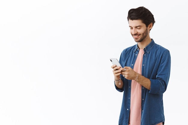 Foto grátis homem vestindo camisa jeans e usando smartphone em branco