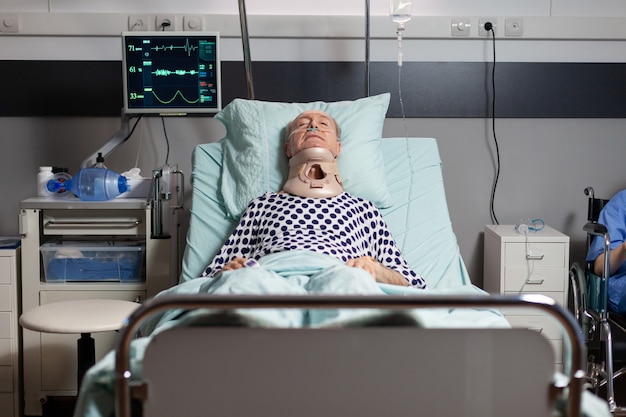 Foto grátis idoso hospitalizado inconsciente na cama do quarto de hospital usando coleira de pescoço com lesão grave de saúde, respirando através de máscara de oxigênio com dor intensa