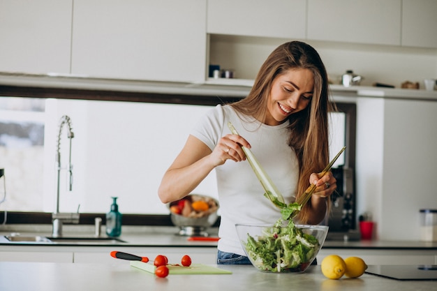 Jovem mulher fazendo salada na cozinha