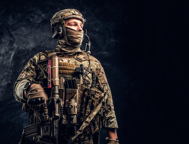 Foto grátis soldado moderno das forças especiais em uniforme de camuflagem, olhando de soslaio. foto de estúdio contra uma parede texturizada escura.