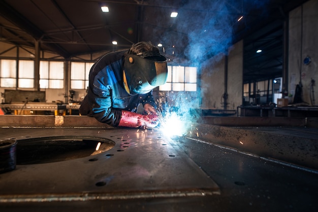 Foto grátis soldador industrial profissional soldando peças de metal em uma fábrica de metalurgia