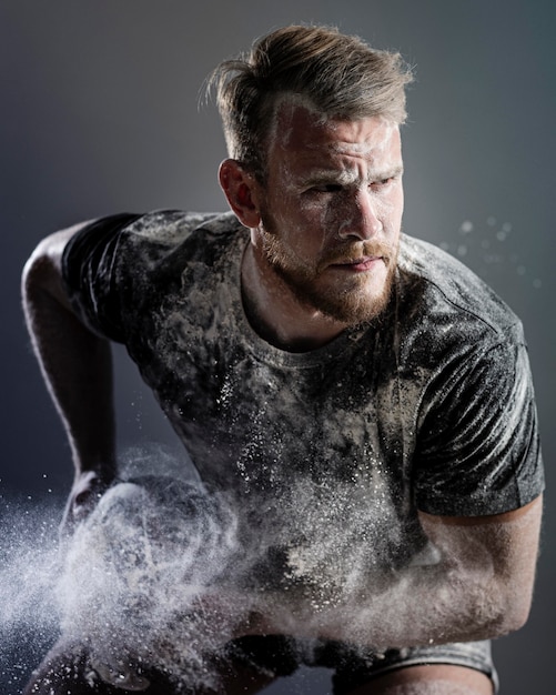 Vista frontal do atleta masculino de rugby segurando uma bola com poeira