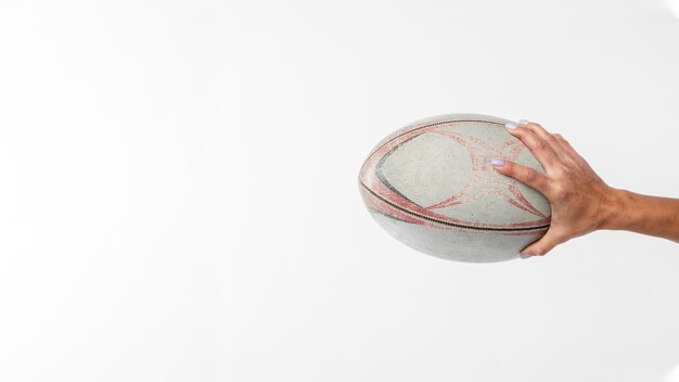 Vista lateral da mão segurando uma bola de rugby com espaço de cópia