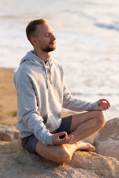 Kostenloses Foto mann meditiert am strand