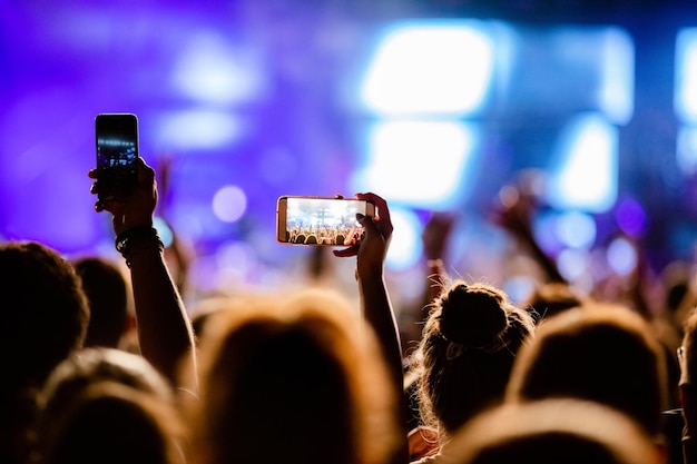 Kostenloses Foto nicht erkennbare person, die mit smartphone-bühnenkünstlern auf dem musikfestival fotografiert