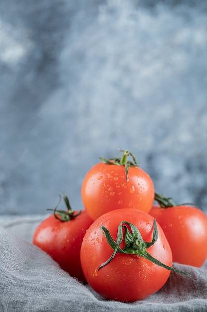 Kostenloses Foto einige frische tomaten auf einer grauen tischdecke.