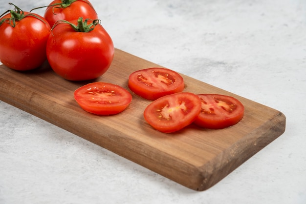 Kostenloses Foto frische rote tomaten auf einem hölzernen schneidebrett