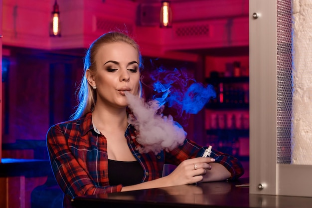 Kostenloses Foto junge hübsche frau in einem hemd in einem käfig raucht eine elektronische zigarette an der vape-bar. vape-shop.