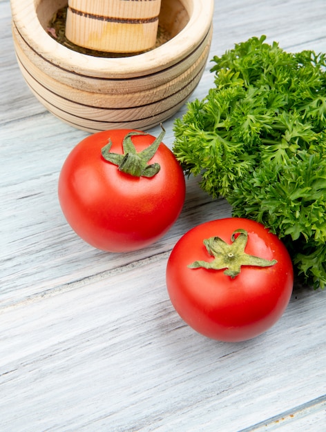 Kostenloses Foto seitenansicht von gemüse als tomatenkoriander mit knoblauchbrecher auf holztisch