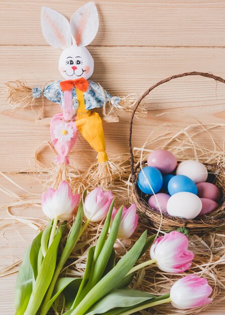 Spielzeugkaninchen nahe Eiern und Tulpen