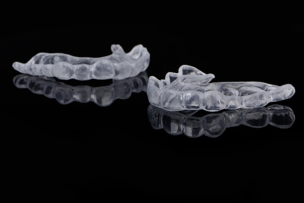 Tapas de silicona de ortodoncia dental sobre un fondo brillante reflectante negro