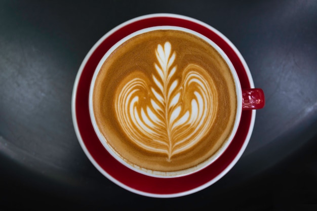 Una taza de café sobre la mesa negra. Vista superior del café latte art. Concepto de bebida y arte.