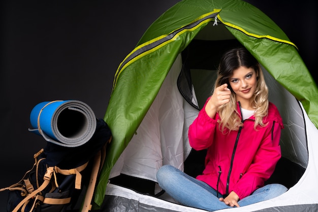 Foto teenager-mädchen in einem grünen zelt des campings auf schwarzer wand, die einen finger zeigt und hebt